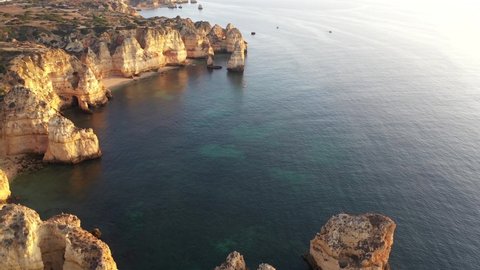 Aerial drone shot revealing small boat travelling in calm water along Algarve coast near Lagos, Portugal