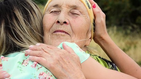 Close-up hugs of grandmother and granddaughter. A gentle hug between granddaughter and grandmother after a long separation. Happy grandmother meets her granddaughter. Trusting relationship
