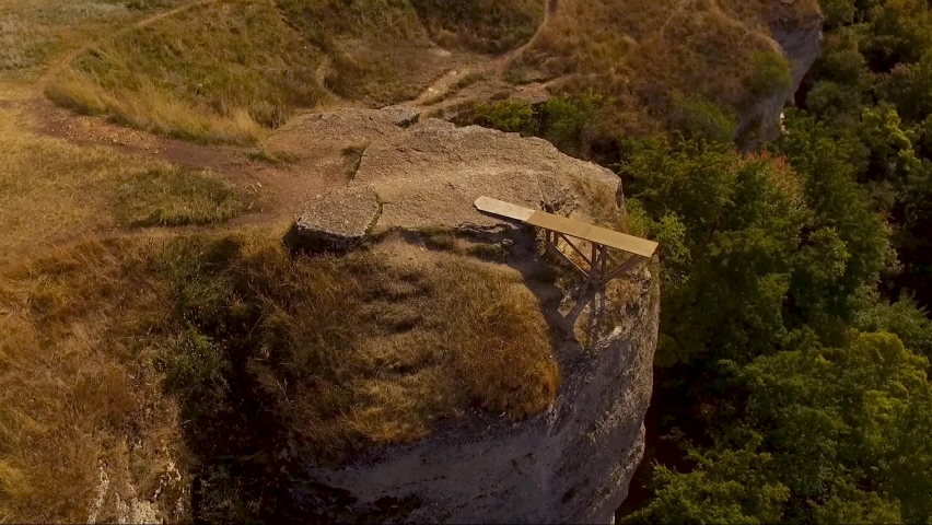 A small wooden bridge on the edge of a rocky cliff. Aerial shot