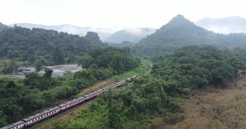 Aerial view of Thailand passenger train pass through the scenic landscape in a green season with foggy in the valley at Kaeng Luang Phrae province Thailand.