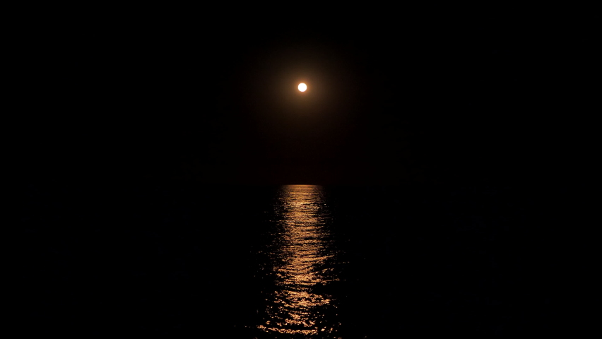 Reflection of the moon in the sea. Full moon at night reflected in the water. moonlight bright sea reflection. A clear large distinct moon shines over the ocean in an eerie night scene