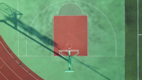 Drone aerial view of the basketball field half court basketball stands hoop. Green basketball court and hoop in the sunny day. Quite no people view of sports calm city life concept Shanghai China