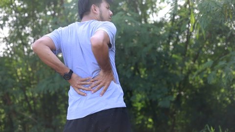 Asian runner sustains a back pain injury, Sports injury, Man with back pain