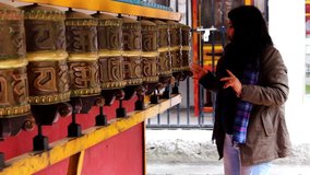 girl spinning Buddhist monastery prayer wheels with hand close up clip
