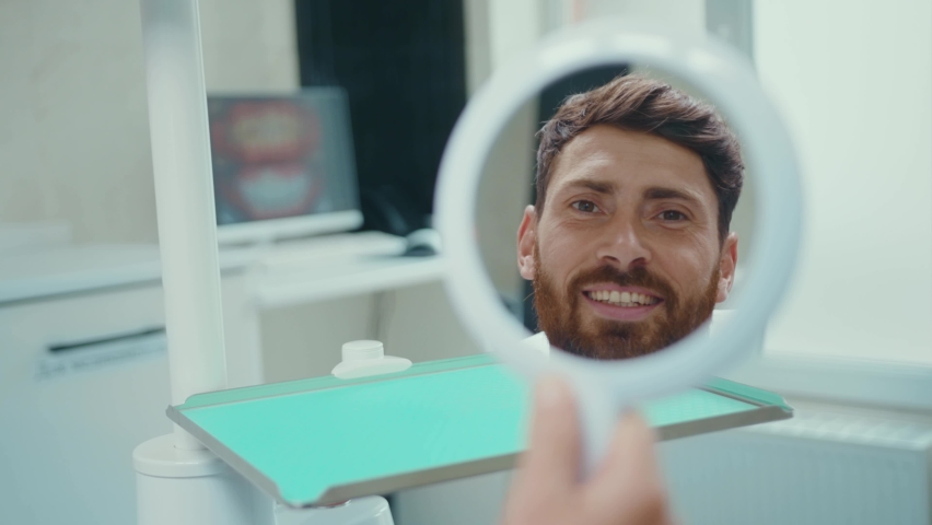 Close up a handsome young male patient in dental chair looking in the mirror talking smiling medical hygiene healthcare teeth patient equipment slow motion. | Shutterstock HD Video #1058607319