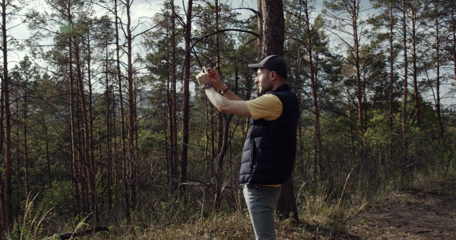 A man takes pictures with his mobile phone, walks in the woods and explores nature. Travel and enjoy the beauty of nature.