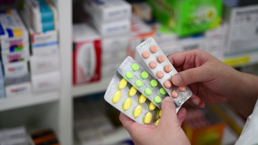 Pharmacist holding medicine capsule pack at the pharmacy drugstore.