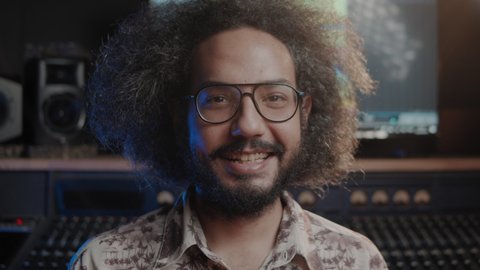 Music production studio. Producer. Portrait of hispanic man working in the recording studio. An attractive male person with afro hair produces songs. 