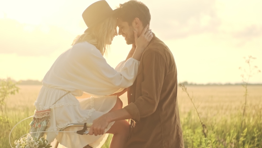 Lovely calm couple man and woman are hugging together while riding bicycle in the countryside