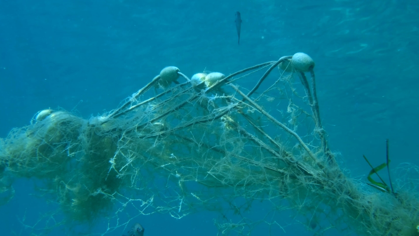 Lost fishing net with buoys lies underwater on the seabed. Problem of ghost gear - any fishing gear that has been abandoned, lost or otherwise discarded. It is the most harmful form of marine debris Royalty-Free Stock Footage #1058616337