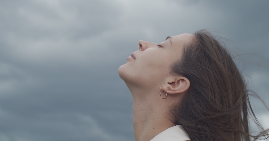 Low angle portrait of woman enjoying fresh air nature life outdoors on cloudy sky background. Beautiful girls face without make up turned up slow motion handheld device. Happiness calmness Royalty-Free Stock Footage #1058625340