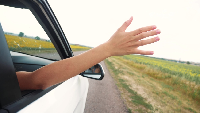 Happy free girl put her hand out and in the car window. c. the girl touches the wind with her hand the view from the car journey window. freedom and happiness | Shutterstock HD Video #1058628391