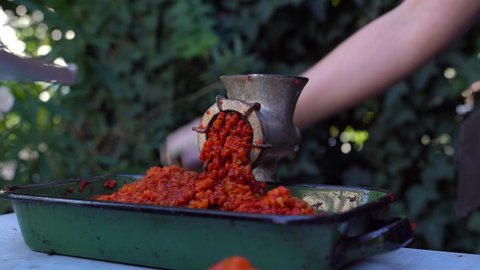 Close up outdoor on female hand on grinder mill for vegetables preparing paprika baked red pepper for ajvar national dish in balkan - healthy organic food concept