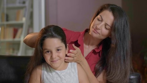 Mother combs her daughter's hair. Woman is brushing her lovely daughters hair in the morning.Mom does the hairstyle of her little daughter's tails, slow motion.Childcare and motherhood concept.4k 