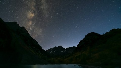 Timelapse time lapse of Maroon Bells lake view of milky way, moon in dark sky in Aspen, Colorado USA at night with Rocky Mountain peak in October autumn