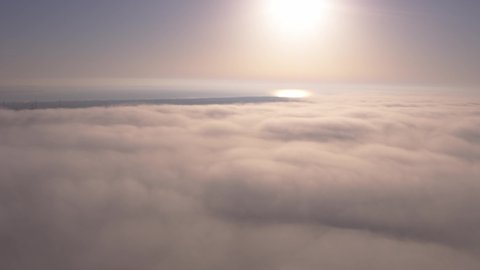 Aerial top view drone flies through heavenly fluffy rain clouds rolling over green forest and field. Foggy morning in pine woodland from above, cloudy, misty weather. Camera flight in low cloud in sky