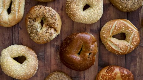 Grabbing a Bagel from a Variety of Bagels on a Wooden Table