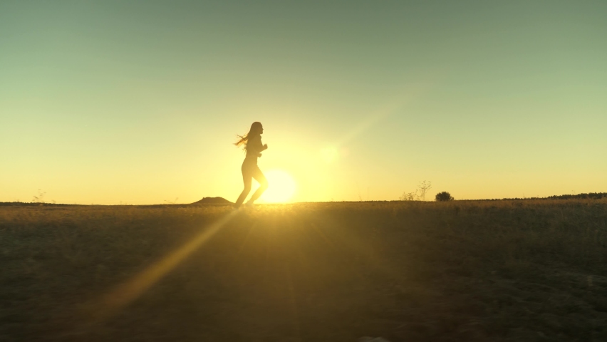 Running after sun. training jogging. healthy beautiful girl is engaged in fitness, jogging in country in sun. Jogger girl breathes fresh air on field. Free young woman runs in summer park at sunset. | Shutterstock HD Video #1058636848