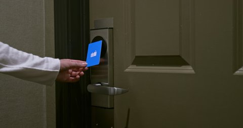 Traveling woman opening the door with blue key card and entering her room in the USA resort. The green and red lights are indicating opening door lock. 4K card key technology, COVID-19 travels