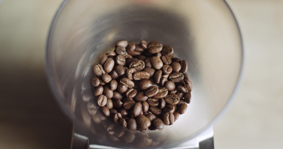 Top view of Aromatic Coffee Beans Grinding and Crushing through Ceramic Burrs and Swirling inside Coffee Basket