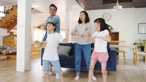 Slow motion - Happy cheerful Asia family having fun listen to music and dancing in living room at modern home. Spending time together, Social distancing, Quarantine for corona virus prevention.