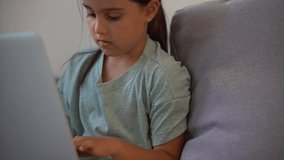 Cute child use laptop for education, online study. Girl has homework at home schooling.