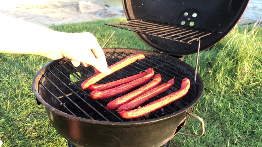 Hunting sausages on the grill. Barbecue in the yard. Bavarian picnic sausages cooked on the fire in a grid