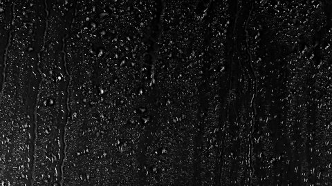 Water Drops following down on black background. Drops of Rain trickling down isolated. Best 4K footage Droplets of Water on Black Glass running down. Perfect for digital composing. 