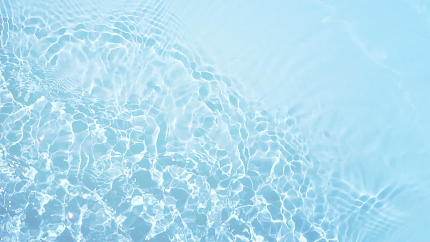 Crystal clear water background. Pure blue water with light reflections in slow motion.  Natural texture top view.