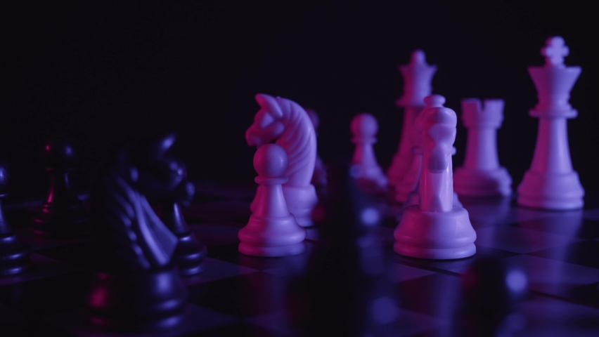 Chess pieces on a chessboard in a colorful fashion style. Studio neon light footage. Pink and purple colors. Slow tracking shot. Fashion, business concept. Depth of field, soft focus . Red camera | Shutterstock HD Video #1058648581