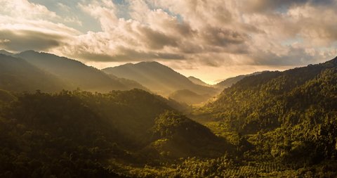 Aerial drone hyperlapse timelapse of beautiful tropical valley between mountains. The first rays of the rising sun break through the clouds and clouds. The last rays of the sunset hit the tree crowns.