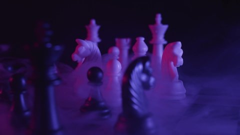 Chess pieces on a chessboard in a colorful fashion style. Studio neon light footage. Pink and purple colors. Creeping smoke. Fashion, business concept. Depth of field, soft focus . Red camera