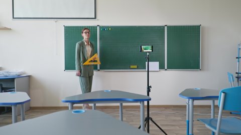 teacher near blackboard using mobile phone video camera recording herself on learning online math education at school, to prevent coronavirus infection during self isolation Vídeo Stock