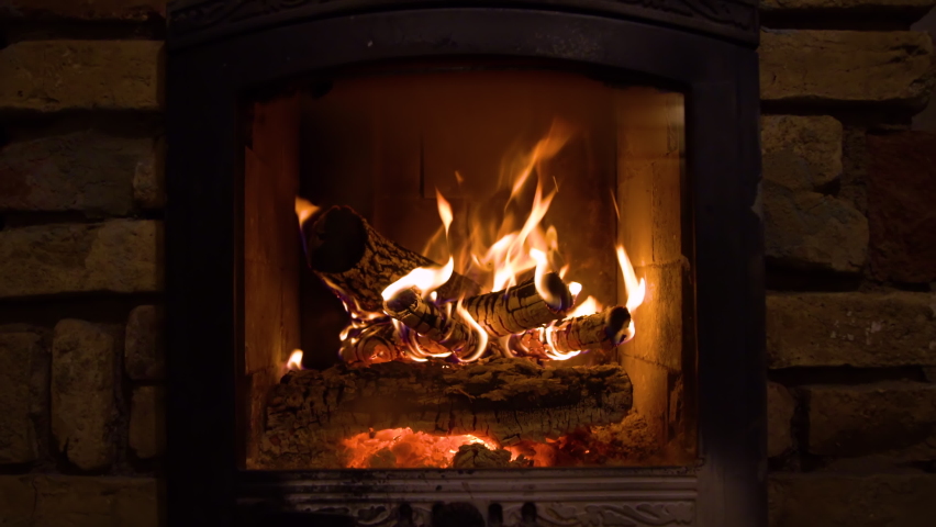 Burning fireplace with wooden logs and flame inside. Warm light, romantic atmosphere indoor | Shutterstock HD Video #1058653444