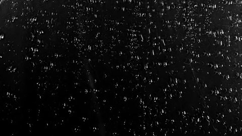 Water Drops following down on black background. Drops of Rain trickling down isolated. Perfect for digital composing. Best 4K High Quality footage Droplets of Water on Black Glass running down. 
