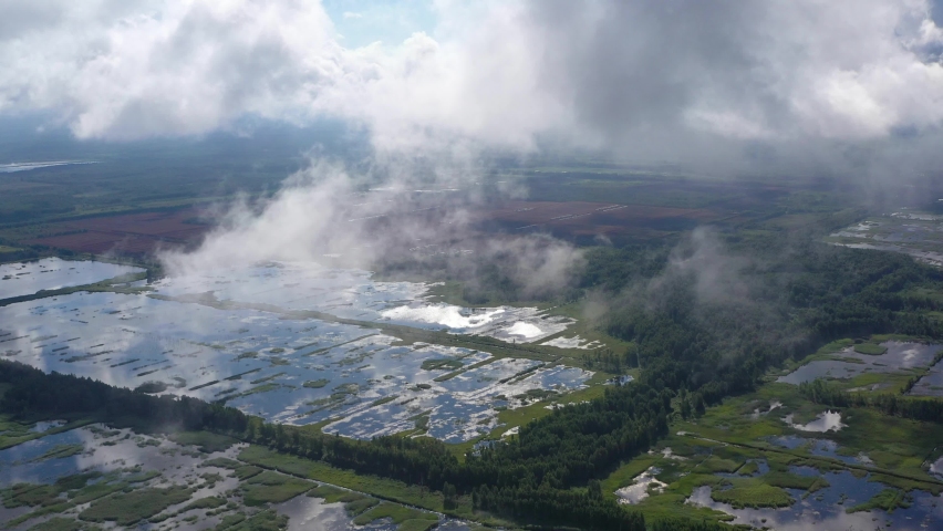 Flying through clouds over flooded Seda swamp (Sedas purvs) lakes and green forests