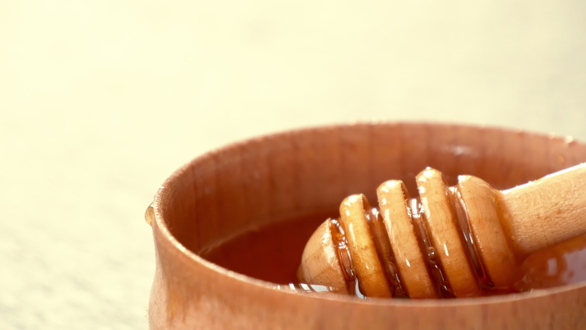 Liquid Organic Honey on a Special Honey Spoon in Wooden Bowl Close Up Shot. Healthy Food Concept. Honey Dripping to a Honey Dipper Royalty-Free Stock Footage #1058664010