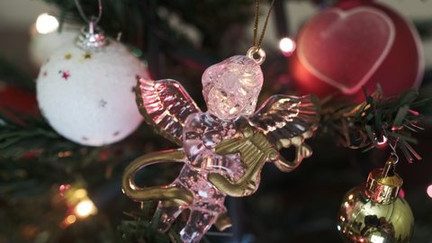 Close-up angel ornament and heart shaped balls on christmas tree. Camera is finding angel figure then focusing softly.