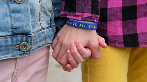 Children hold hands, child with autistic bracelet. Autism Syndrome Concept