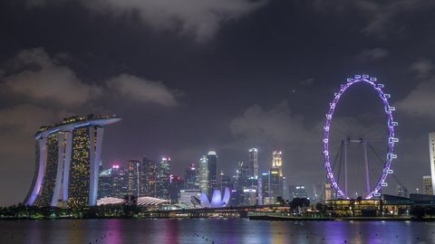 Downtown skyline of Singapore as viewed from across the water from The Garden East night timelapse hyperlapse. Singapore. Reflection in water with illuminated skyscrapers