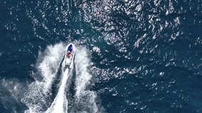 Aerial drone video from jet ski watercraft making extreme manoeuvres while cruising in high speed over deep blue open ocean sea