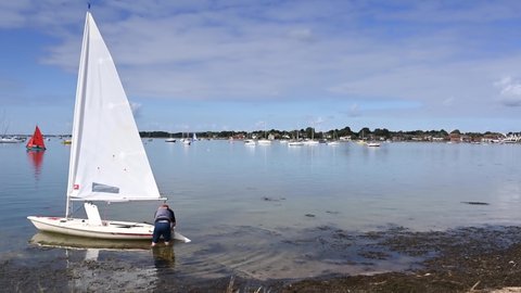 Emsworth, Hampshire, UK, August 31, 2020. Footage of the beautiful Emsworth Harbour with a dinghy preparing to set sail and Yachts in the background.