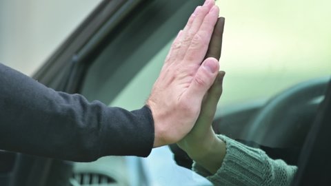 Farewell of two people. The man and the woman put their hands on the glass of the car, then the woman removes her hand and the car drives away. Parting and goodbye symbol