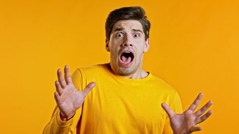 Young scared man shouting loud isolated over yellow background. Stressed and depressed guy trying to get attention. Concept of help and safe