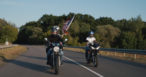 Bikers with the U.S. flag are driving on the highway. Freedom and allusion concept