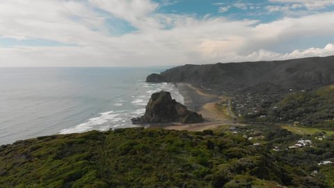 Aerial view revealing Lion Rock at black sand Piha Beach, New Zealand