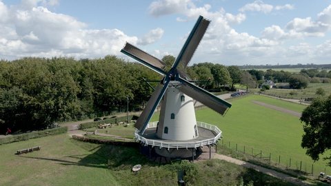Flying away from rotating windmill, revealing beautiful green meadows
