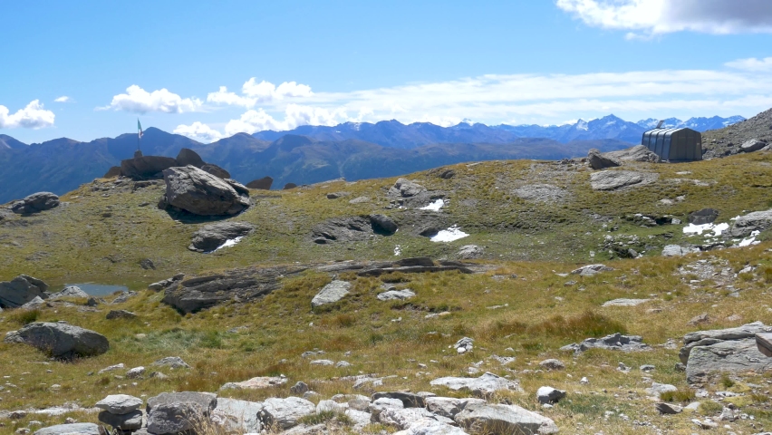 Alpine landscape high altitude mountain range and glaciers, green valley, snowcapped mountain ridges and peaks against clear blue sky, the Alps.