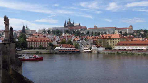 PRAGUE / CZECH REPUBLIC - JULY 2020: View of Prague Castle from Charles Bridge, tourist landmark on the Vltava river in Prague, Czech Republic, Europe. City landscape with ferry boat, monument
