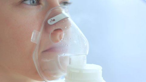 Sick woman with a sore throat makes inhalation with a mask on his face. Sick patient heals itself nebulizer